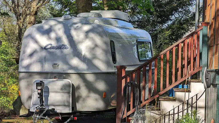 A small travel trailer parked beside a house