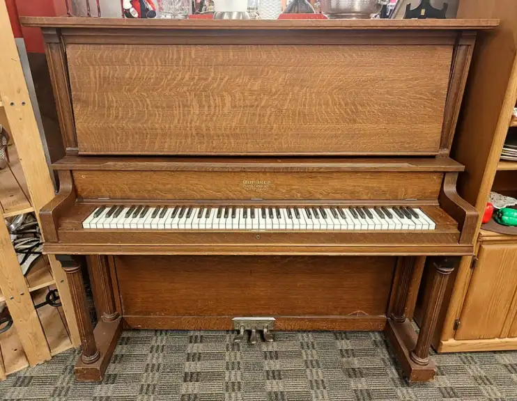 An upright wooden piano with a bench
