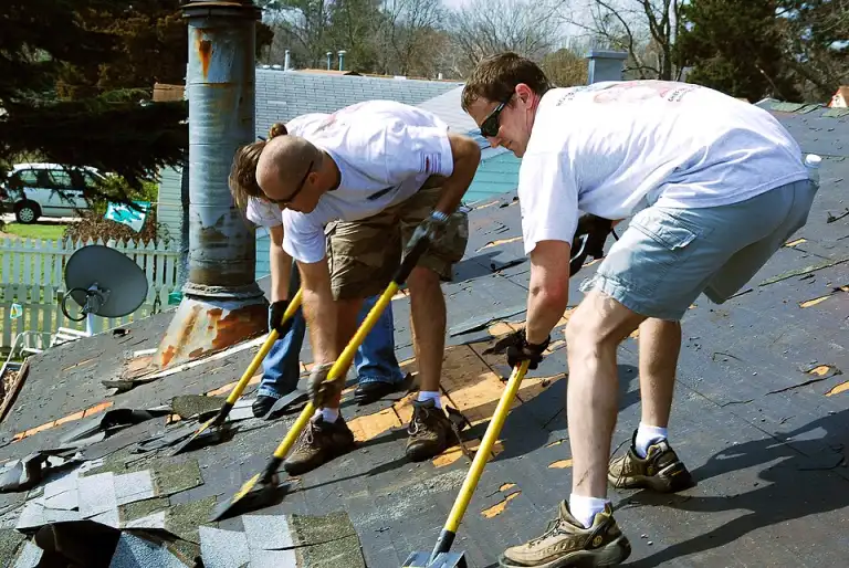 Workers removing old roofing felt and shingles
