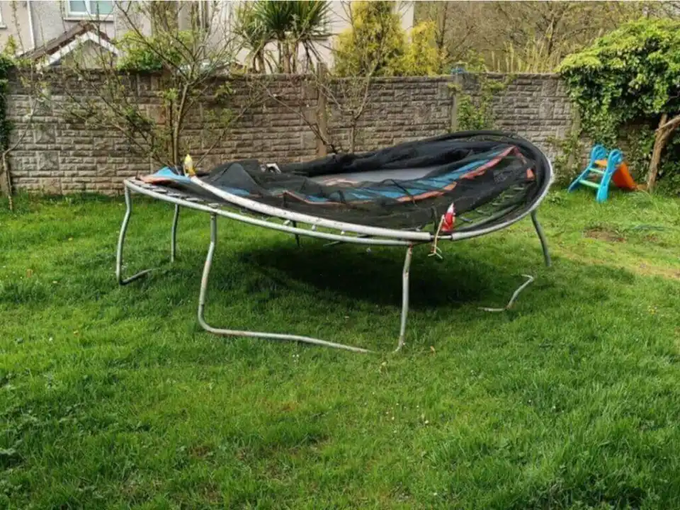 A damaged trampoline standing in a backyard